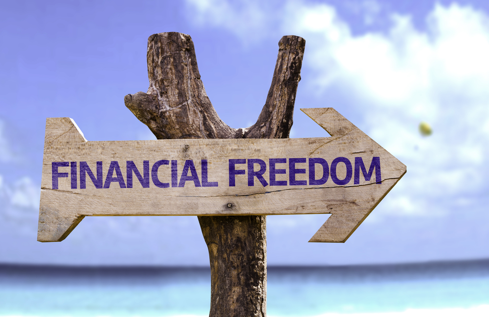 Wooden arrow sign labeled Financial Freedom on beach