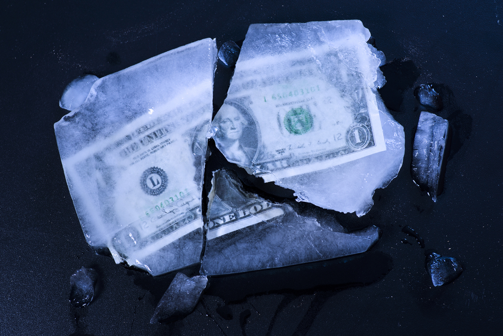 Dollar bill frozen in ice and cracking apart