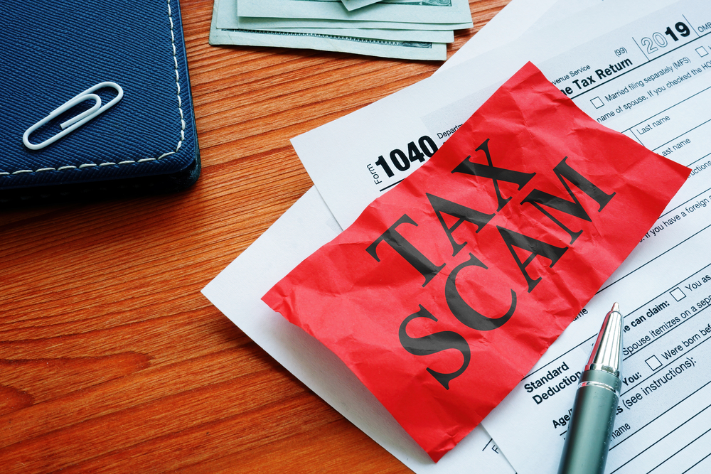 Red note reading Tax Scam on top of IRS forms