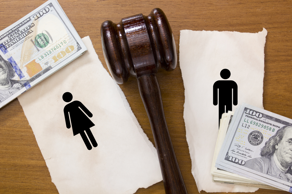 Torn piece of paper with man and woman silhouettes with money and judge's gavel
