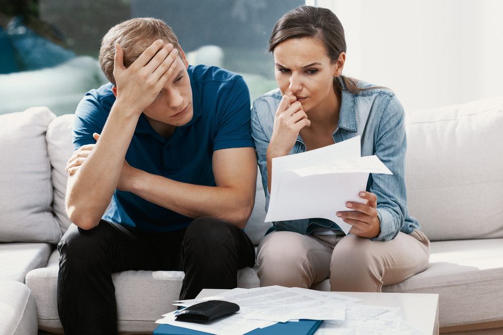 Husband and wife looking over financial documents and appearing worried