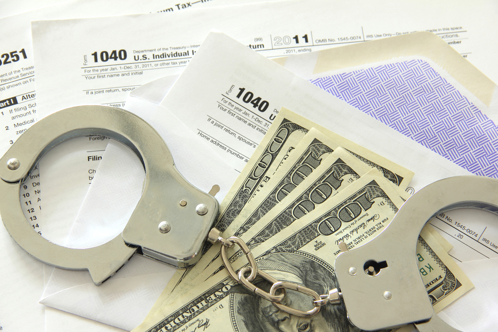 Handcuffs on top of $100 bills and tax forms