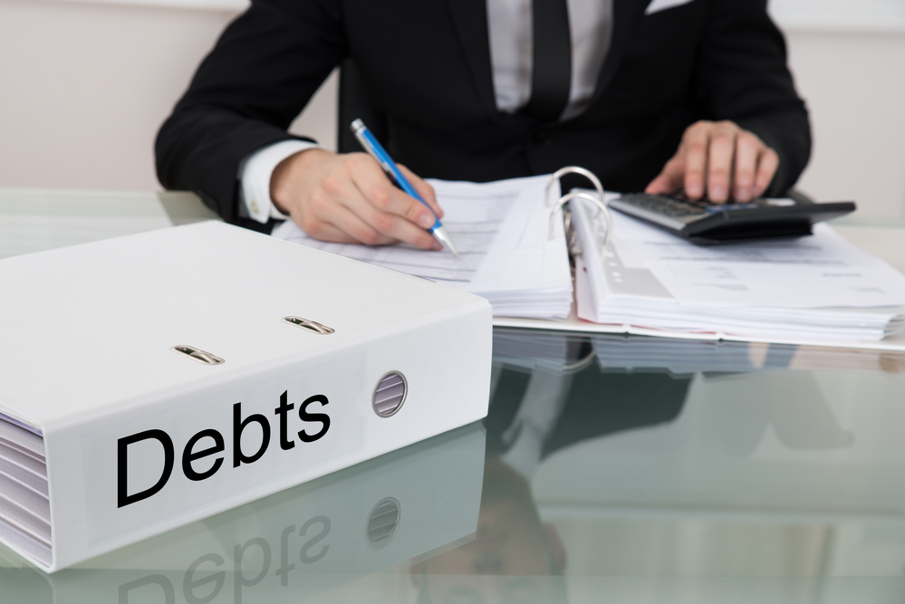 Business man reviewing finances with debts binder on desk