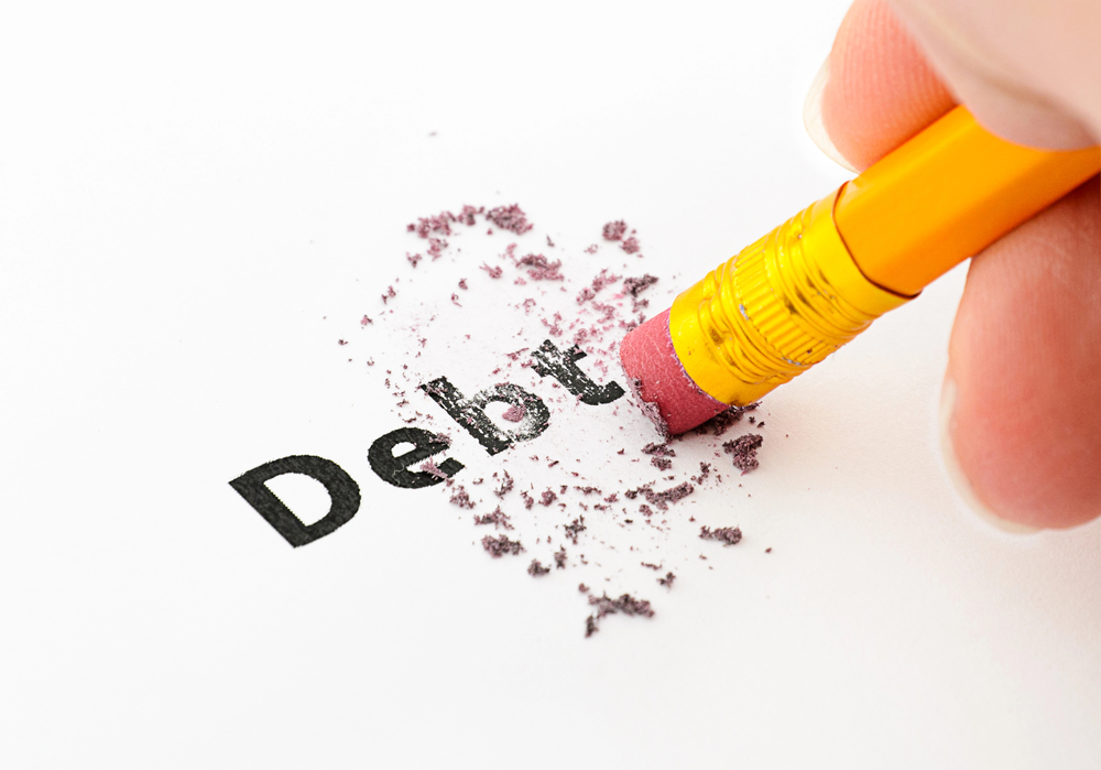 Hand with pencil erasing the word debt