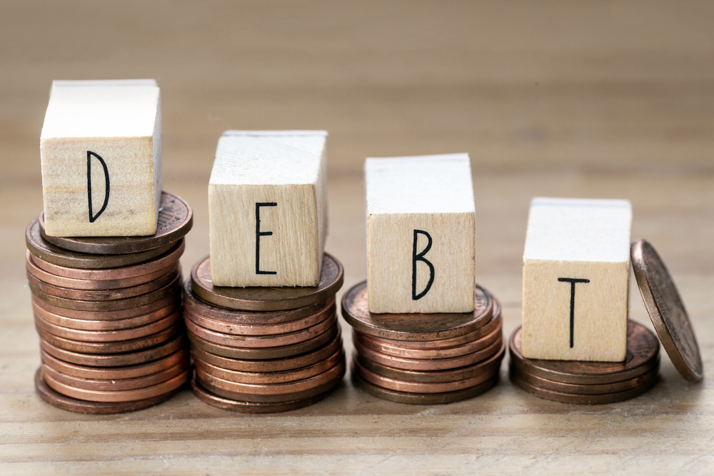 Debt written on wooden blocks on stacks of pennies