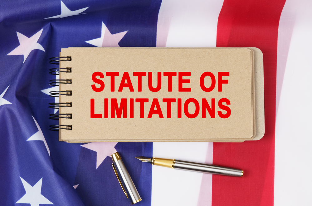 Notebook reading "statute of limitations" on top of American flag