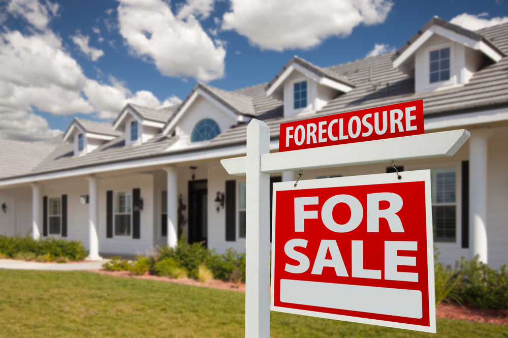 Foreclosure for sale sign in front of large white house