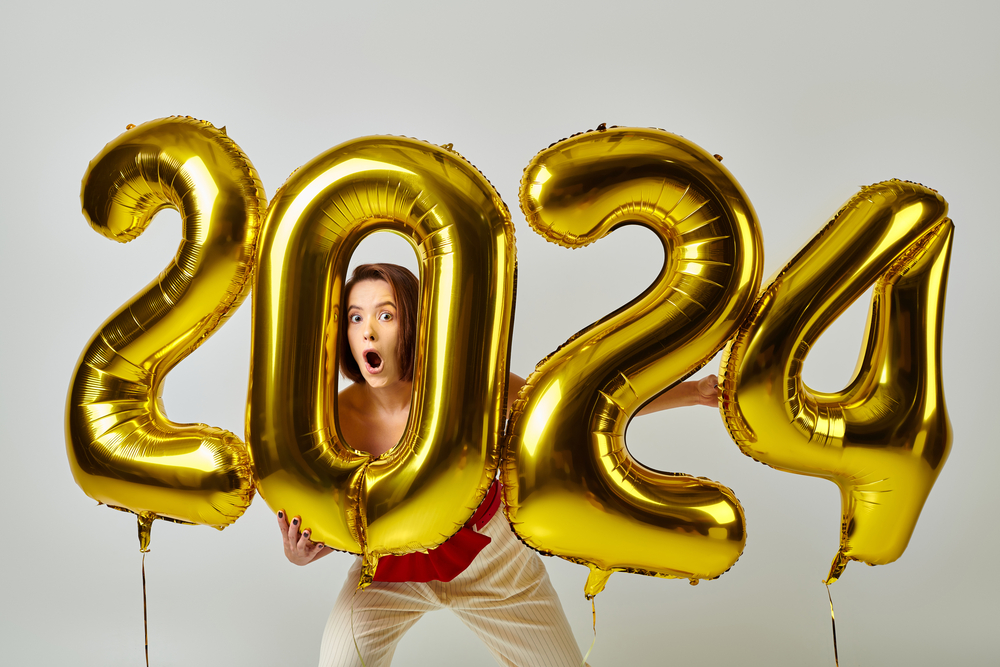 Woman holding gold 2024 balloons and looking through the 0