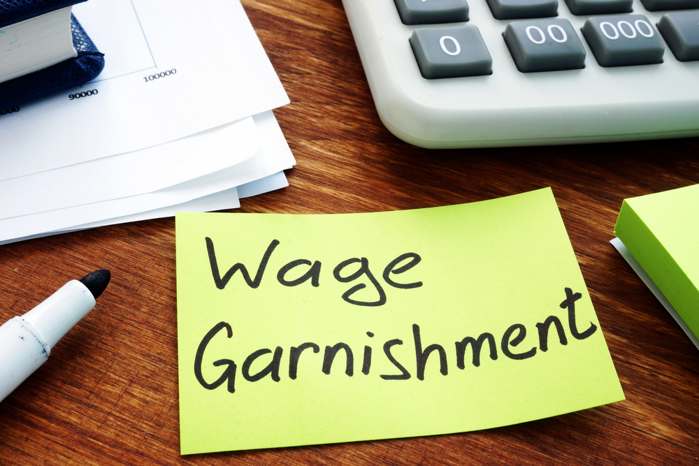 Wage garnishment written on sticky note next to calculator