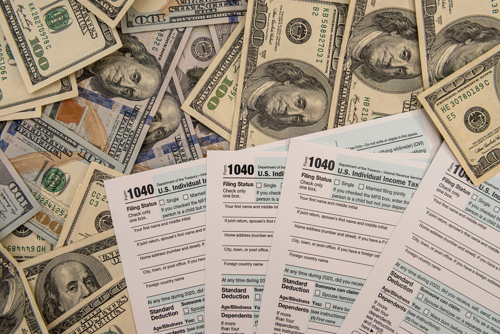 IRS 1040 forms on top of $100 bills